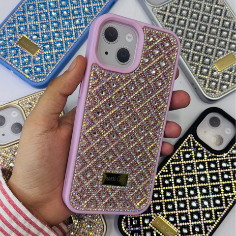 Hand holding a pink and gold embellished phone case with other embellished cases in the background.
